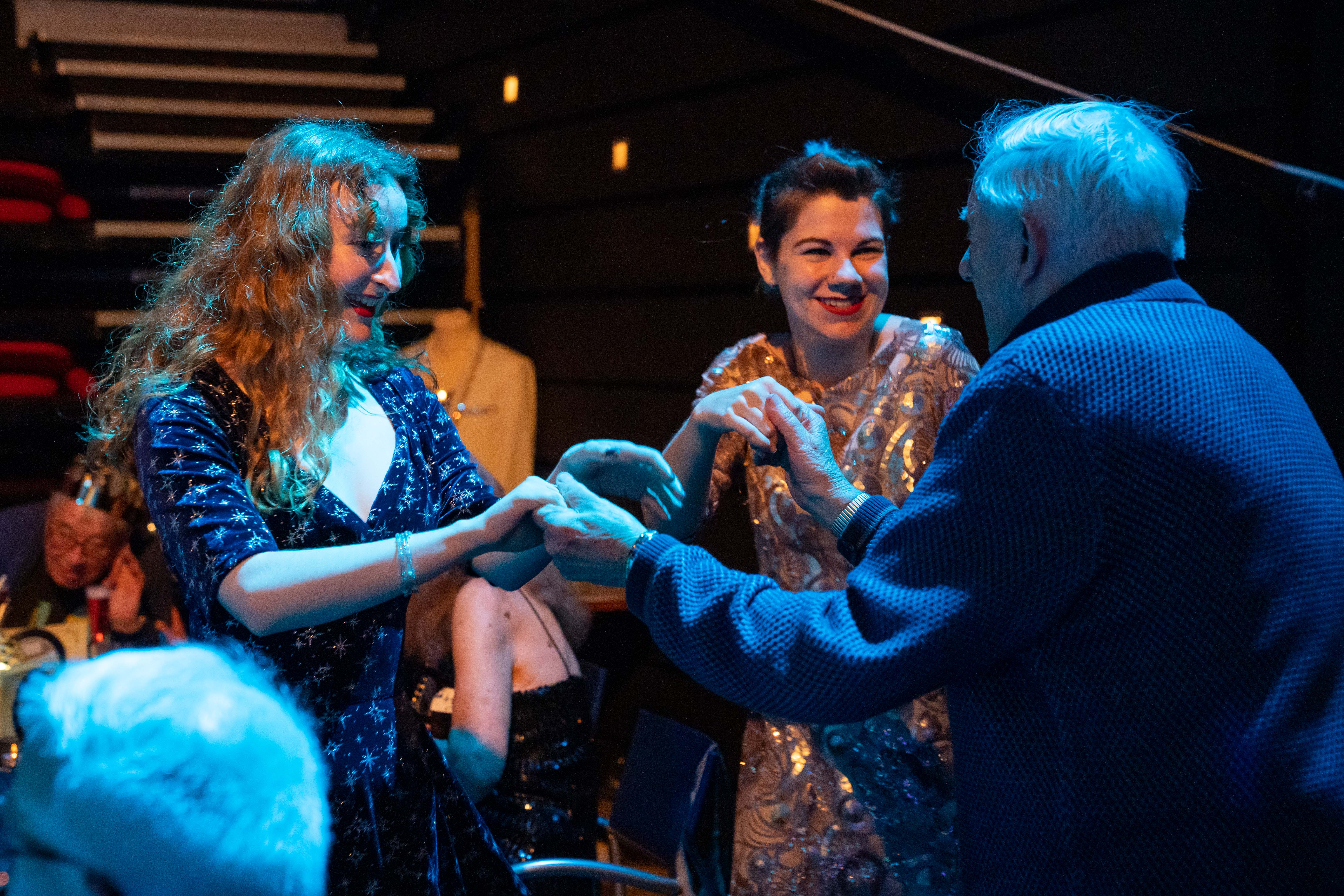 A group of people joining hands and laughing