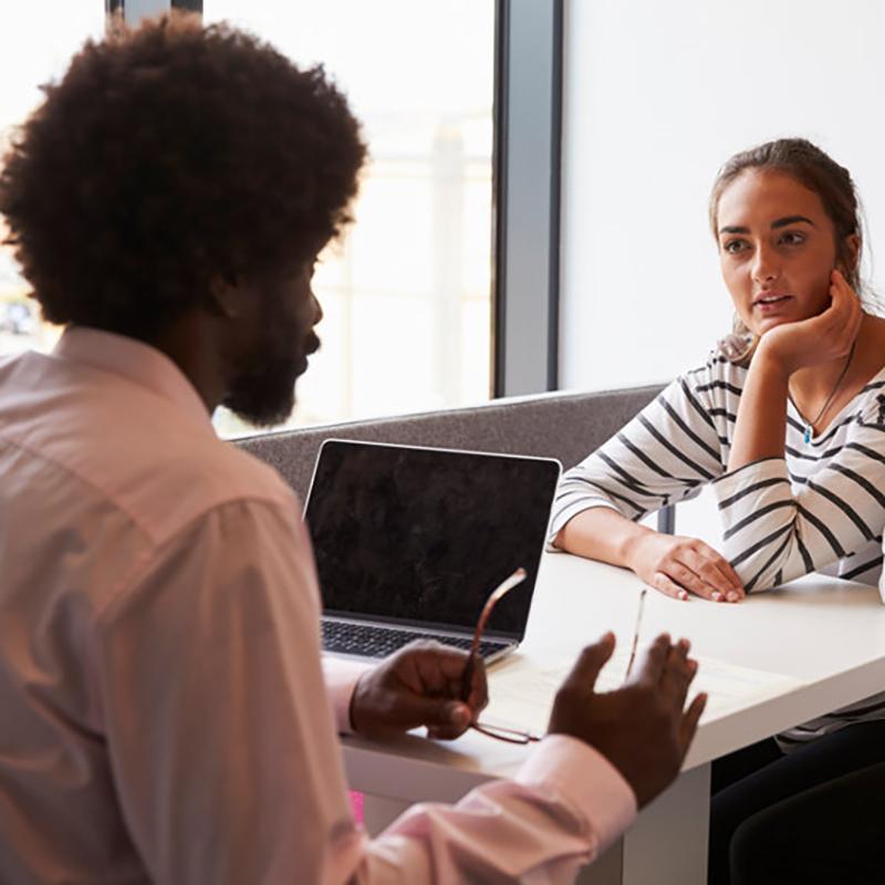 Man and woman sat at desk in discussion