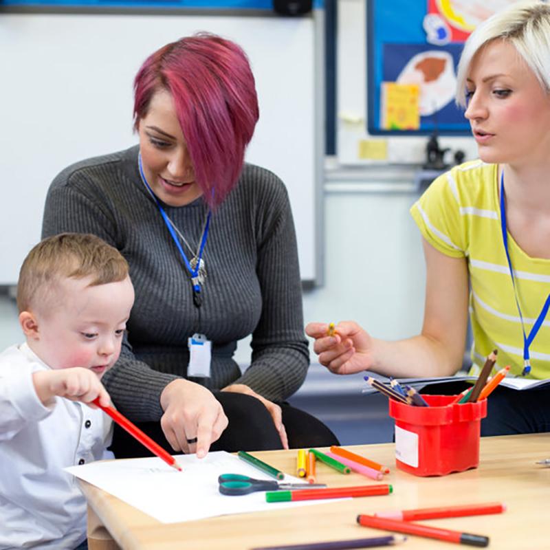 Young boy with two carers in school setting