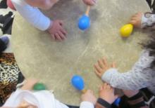 Baby hands holding shaker rattles reach out on a drum's surface