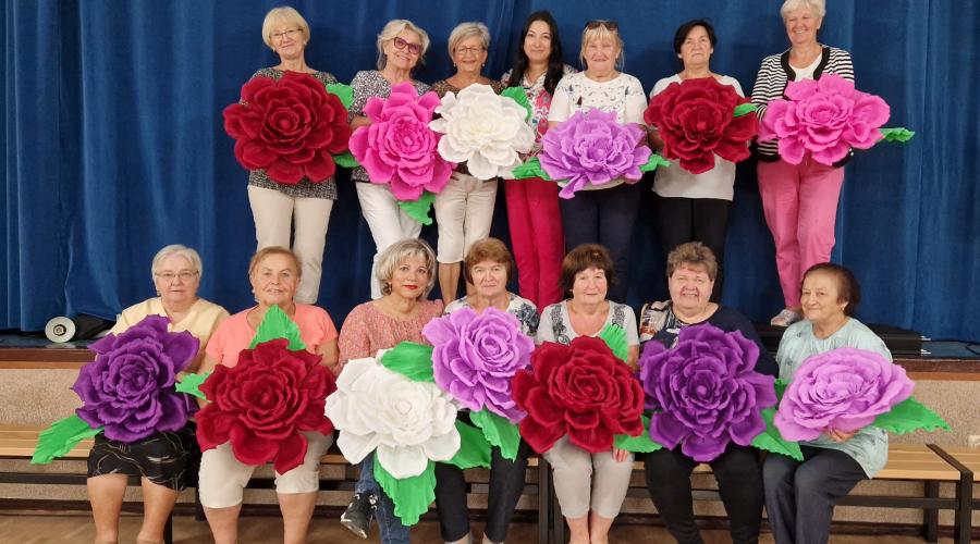 a group of ladies holding large paper flowers